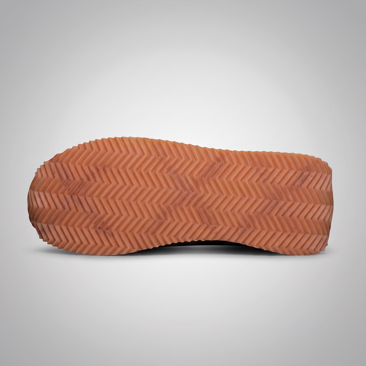The textured rubber outsole of a shoe, shown from a top-down view against a light gray gradient background.